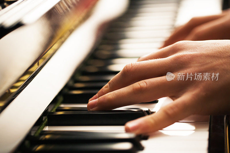 一个年轻人的特写的手弹钢琴